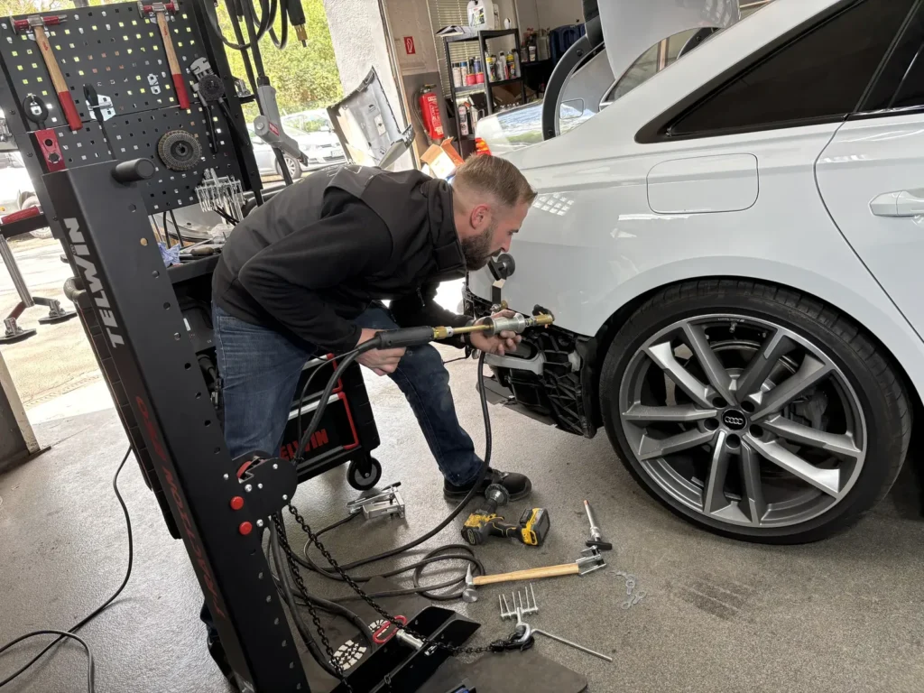 Kfz-Techniker beim Ausbeulen mit Zugtechnik