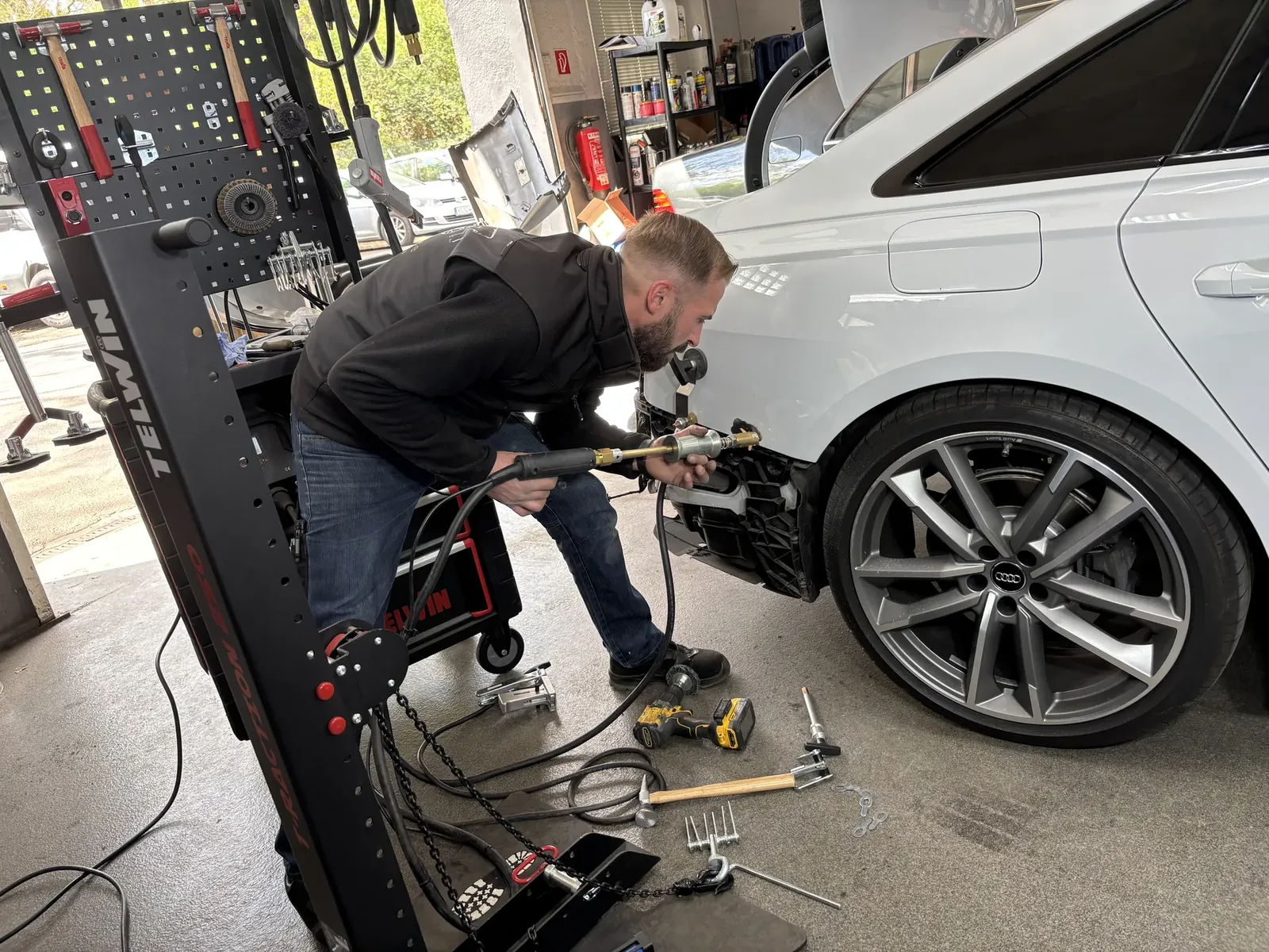 Kfz-Techniker bei der Karosserie-Instandsetzung mit Zuggerät